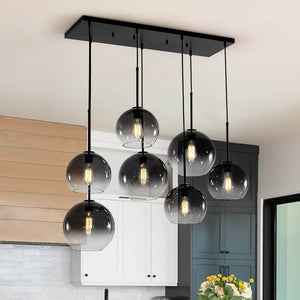 Introducing our 7-light unique modern gradient smokey grey glass globe chandelier, designed to bring a touch of sophistication to any space. Its sleek matte black frame beautifully contrasts with the soft, smoky gradient of the glass globes, creating a striking visual centerpiece. Whether hanging above your kitchen island, dining room table, living room, bedroom, or bar, this chandelier effortlessly elevates the ambiance of any space.